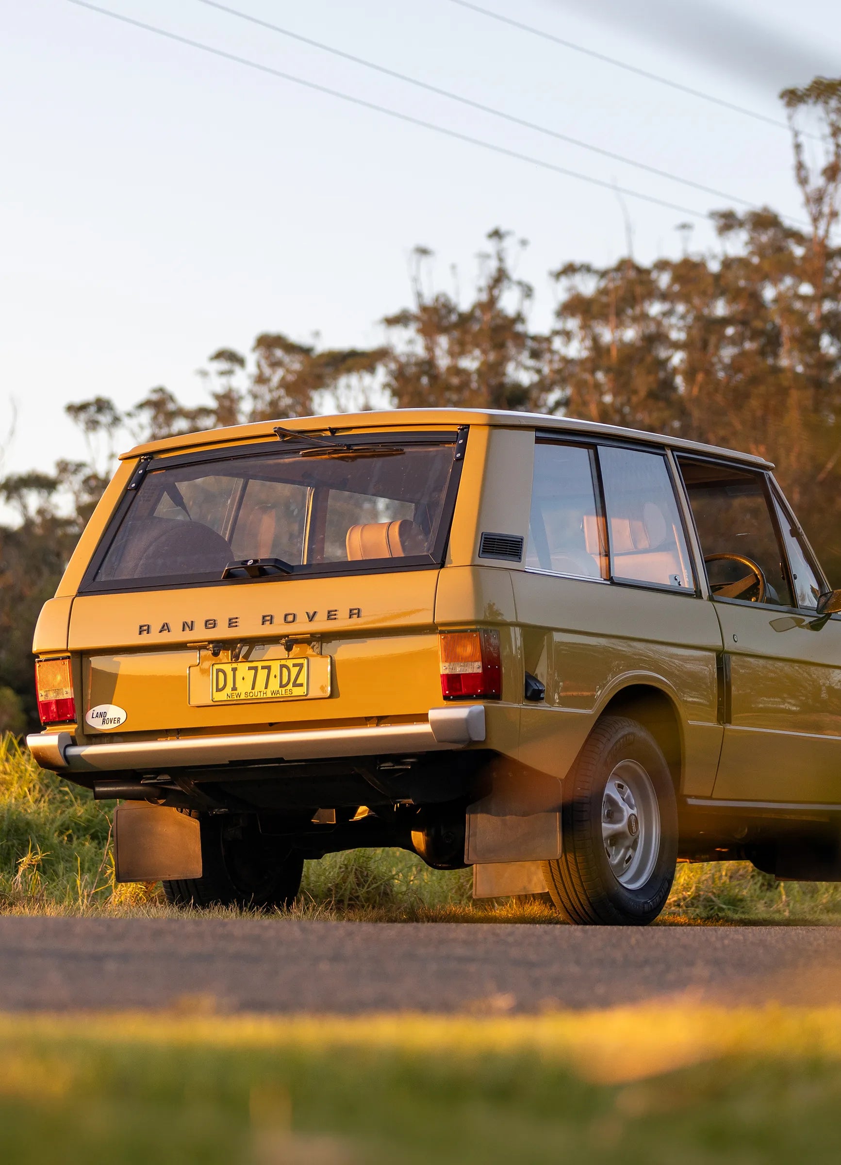 Vintage yellow Range Rover parked on a road with trees in the background restored by Hudson Coachworks | Range Rover Classic | Range Rover Restoration | anger Rover Build | Range Rover Coachworks | Classic Range Rover
